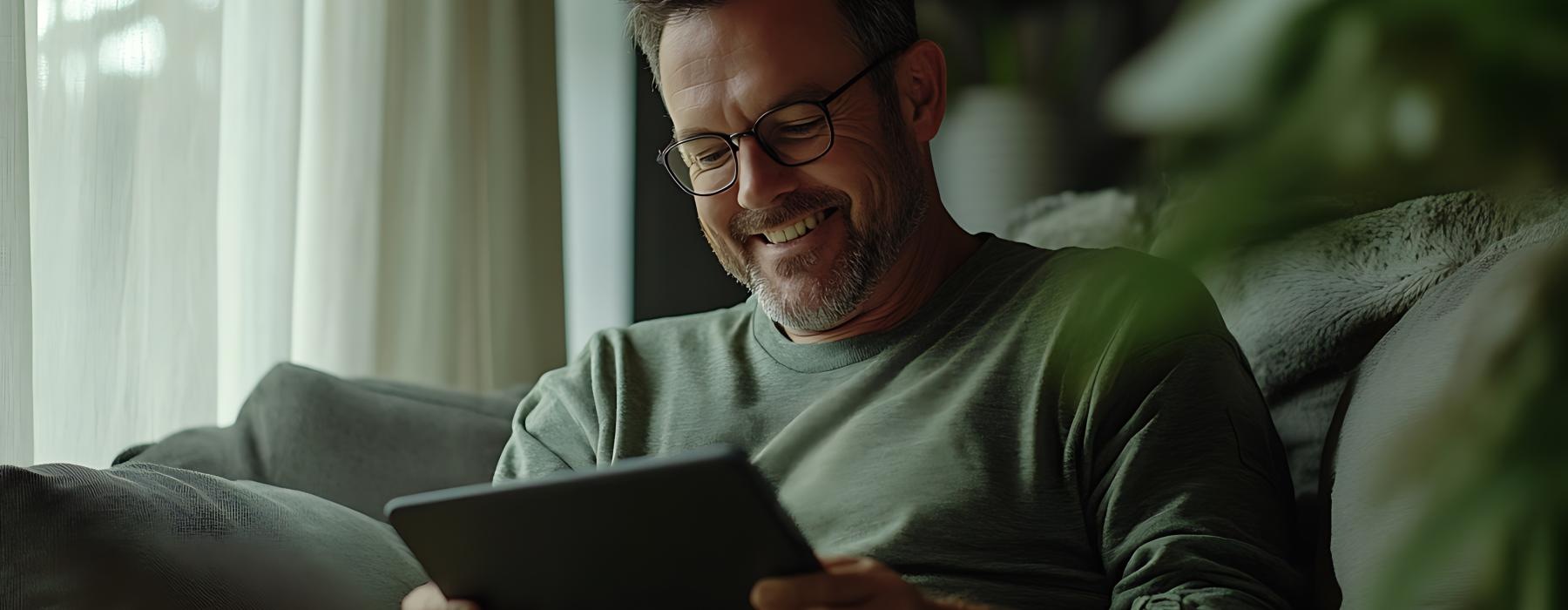a man sitting on a couch and holding a tablet